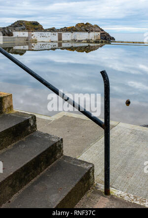 A view of concrete steps and a broken metal railing outside Tarlair Swimming pool, now abandoned and derelict, near MacDuff, Aberdeenshire, Scotland Stock Photo