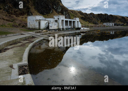Tarlair Swimming Pool, long since abandoned, now lying empty and surrounded with dirty sea water, near MacDuff, Aberdeenshire, Scotland Stock Photo