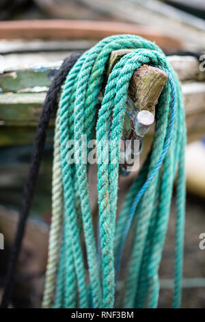 A green nylon mooring rope placed over the bow of a small fishing boat in Gardenstown harbour, Aberdeenshire. Stock Photo