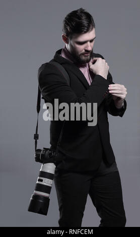 professional photographer with camera, adjusting a cufflink.isolated on grey background Stock Photo