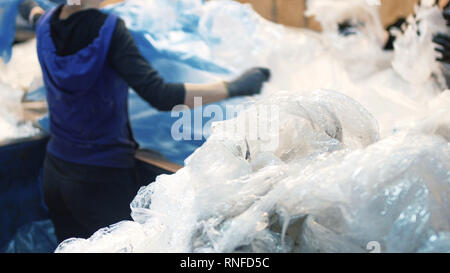 Workers select and sort garbage that travels on a conveyor belt in a waste recycling plant. Stock Photo