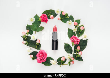 top view of circular composition with green leaves, flowers and pink lipstick isolated on white Stock Photo
