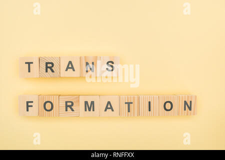 top view of transformation lettering made of wooden cubes on yellow background Stock Photo