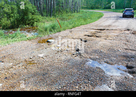 A washed out gravel road with a vehicle in the background Stock Photo