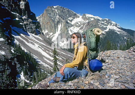A female backpacker rests on a scree slope as she negotiates a rugged and alpine section of the Continental Divide Trail in the San Juan National fore Stock Photo