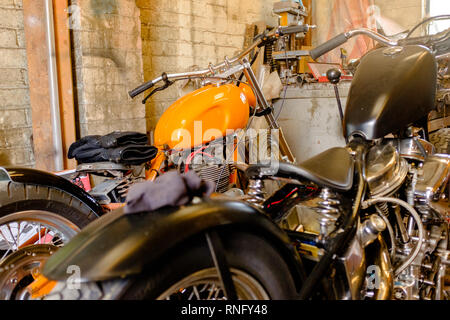 Interior view of local motorcycle workshop garage full of various motorbikes and spare parts under repair Stock Photo