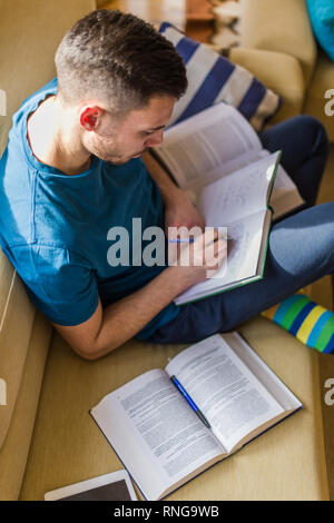 A handsome man is taking notes while learning from the book Stock Photo