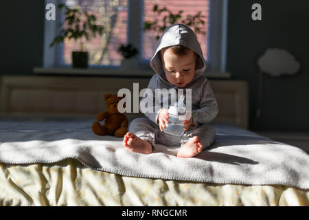 Baby boy with coloured pyramid toy on bed in his room Stock Photo