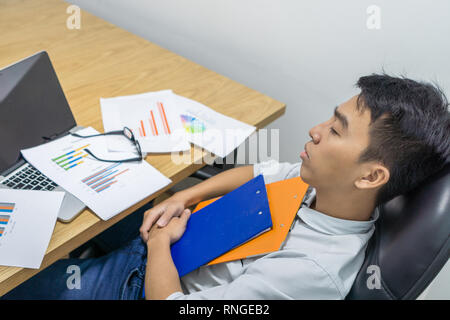 Office man sleeping with financial reports on the table Stock Photo