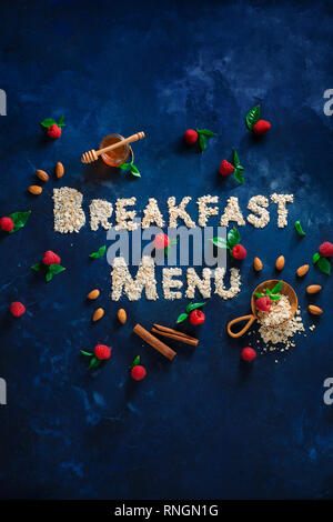 Breakfast Menu words written with oatmeal with raspberries and cinnamon. Healthy eating concept on a dark background with copy space. Stock Photo