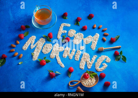 Good Morning words written with oatmeal, raspberries and cinnamon. Healthy eating concept on a vibrant fresh background with copy space. Stock Photo