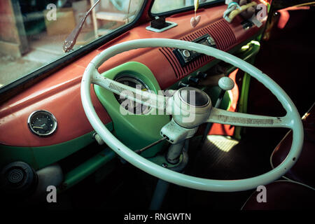 Looking through side window into split screen vw camper van with basic classic design dashboard and steering wheel interior. Stock Photo