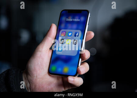 Group of Social Media Application Icons On Iphone X Smartphone in Hand Holding Stock Photo