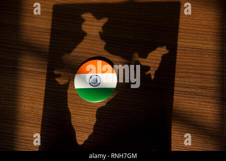 India flag badge kept on a brown background in shadow of Indian map Stock Photo