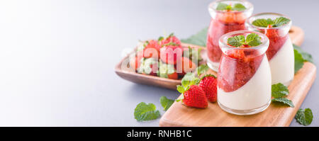 Delicous and nutritious double color (colour) strawberry desserts with mint and diced sarcocarp topping isolated with airy blue background, copy space Stock Photo