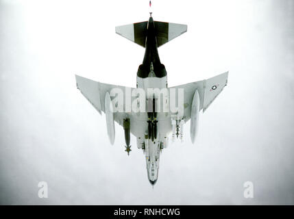 1980 - An underside view of an F-4E Phantom II aircraft in flight.  Auxiliary fuel tanks are mounted on each wing.  A Mark 84 bomb is on the left wing and two AIM-9L Sidewinder missiles on the right.  A Pave Spike airborne laser designator is mounted on the left side of the fuselage and six Mark 82 500-lb. low-drag bombs on the centerline Stock Photo