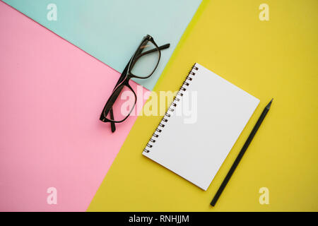 Notepad, glasses and a pencil on a multi-colored background. Stock Photo