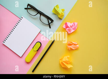 Blank notepad for text, glasses and other items on a multi-colored background. Stock Photo
