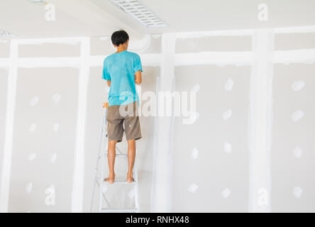 gypsum board wall interior decoration of home and worker male motion on stair is putting plaster at construction site with copy space add text Stock Photo