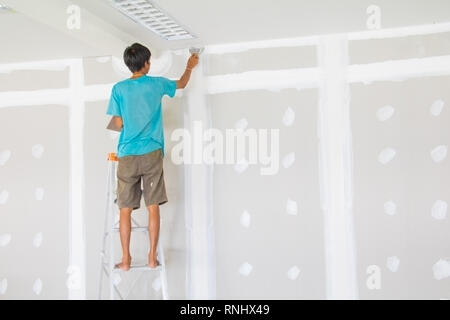 worker male on stair is putting  gypsum plaster interior decoration of home wall Stock Photo