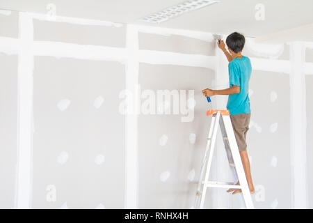 worker male on stair is putting  gypsum plaster interior decoration of home wall Stock Photo