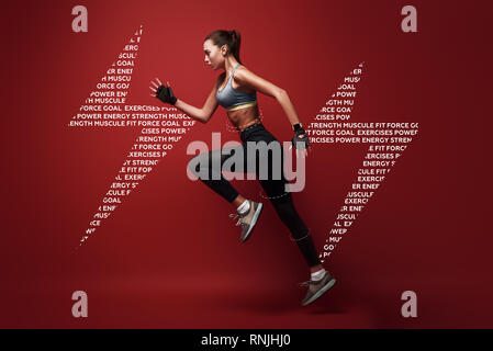 Full length portrait of a healthy muscular sportswoman jumping  over red background. Dynamic movement. Side view Stock Photo