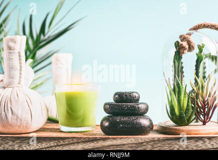 Spa concept with massage equipment:  stack of massage stones,  aromatherapy candles,  herbal stamps setting on wooden table with succulent plants at l Stock Photo