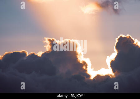 Sunbeam shinning through clouds; sunset colors Stock Photo
