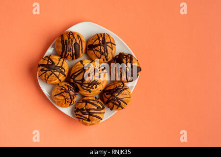 Traditional French dessert. Eclair with chocolate icing. Pastry concept on coral color background. Flat lay or top view. Stock Photo