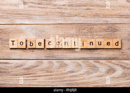 To be continued word written on wood block. To be continued text on wooden table for your desing, concept. Stock Photo