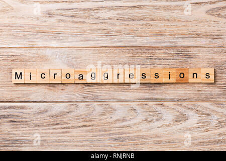 Microaggressions word written on wood block. Microaggressions text on wooden table for your desing, concept. Stock Photo