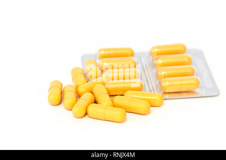 Bright yellow pills and blisters scattered on a white background. Isolated Stock Photo