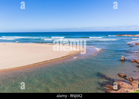Scenic beach blue water ocean and river mouth at Scottborough a distant surfer walking sandbank going surfing fishing sporting holiday landscape. Stock Photo