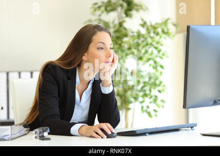 Confused and bored office worker checking computer content at workplace Stock Photo