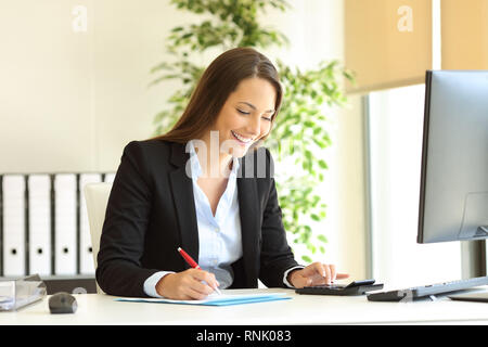 Happy office worker working calculating and writing budget on a desktop Stock Photo