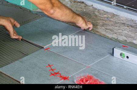 Worker installing floor tiles at home Stock Photo
