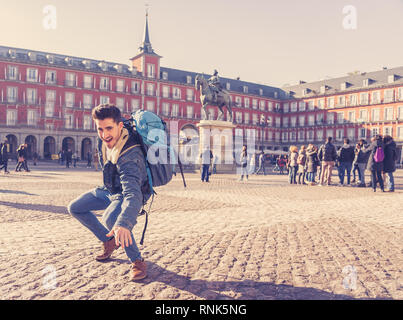 Happy young man traveling around Europe having fun pretending to surf in Plaza de Espa–a, Madrid, Spain. In People Vacations, adventure, backpacking,  Stock Photo