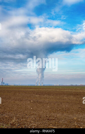 Cooling towers of nuclear power plant (NPP) Jaslovske Bohunice (EBO) in Slovakia. Clouds of thick smoke from chimneys on blue sky at winter day. Cooli Stock Photo