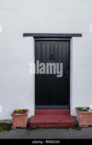 A black front door with two plant pots on either side Stock Photo