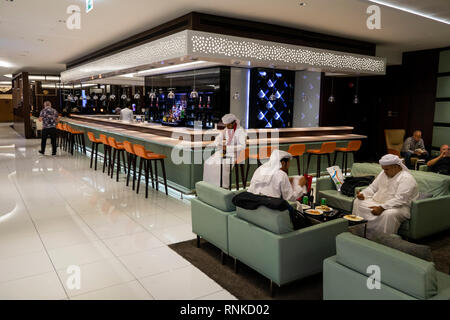 United Arab Emirates Abu Dhabi Airport, Terminal 3, Business Class Lounge, Arab passengers eating at tables near bar Stock Photo