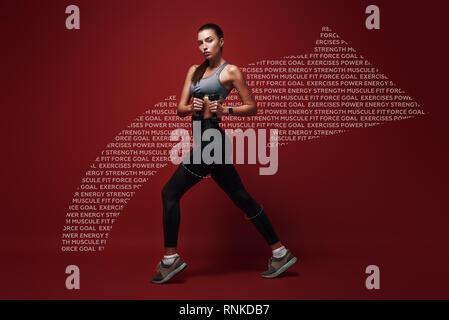 Full length portrait of a healthy muscular sportswoman standing  over red background with dumbbells in her hands. Dynamic movement. Side view Stock Photo