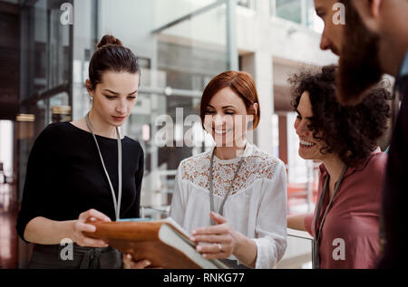 Group of young businesspeople standing together in office, talking. Stock Photo
