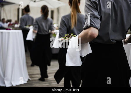 Waiter carrying plates with meat dish on some festive event Stock Photo