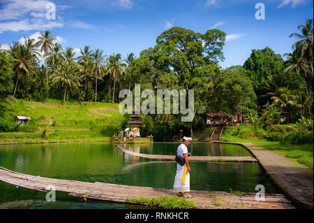 Balinese man in traditional dress visiting Tirta Taman Mumba water temple to celebrate a religious holiday. Beautiful lake, nature landscape Stock Photo