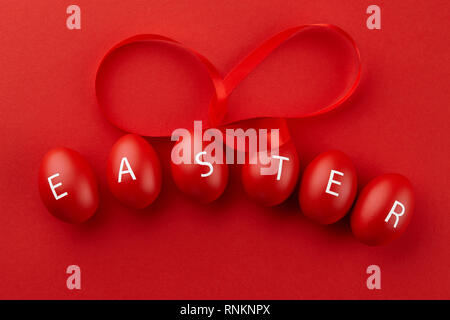Red Easter eggs with letters arranged in a word Easter on red background. Holiday concept. Stock Photo