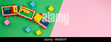 Toy background. Wooden toy train with colorful cubes on pink and green background Stock Photo