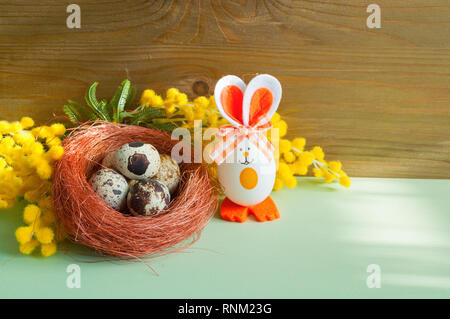 Easter background. Easter bunnies and Easter eggs in the box near the mimosa flowers, free space for Easter text Stock Photo