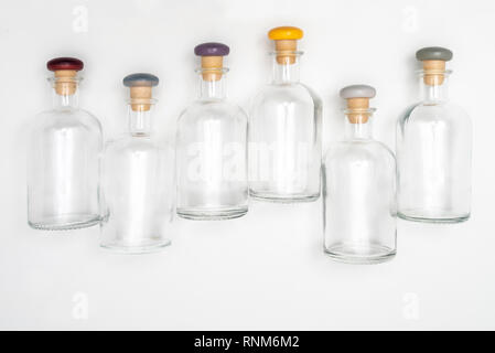 small glass bottles with the colored cap lined up on a white surface Stock Photo