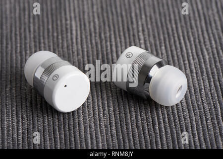 close-up of wireless cordless bluetooth stereo earbuds on a fabric background Stock Photo