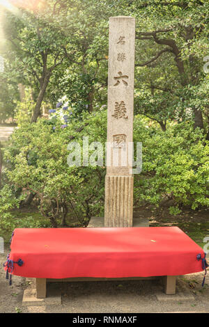 Rectangular stone testifying the status of Japanese national scenic site in the Rikugien Garden in Tokyo. Wooden benches covered with red felt are ava Stock Photo